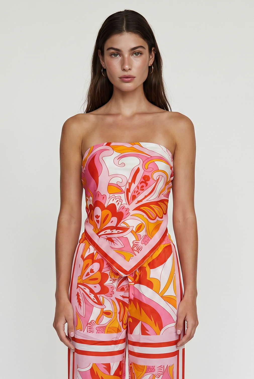Image shoes a girl thigh up standing straight looking at the camera wearing a printed strapless top and matching pants.
