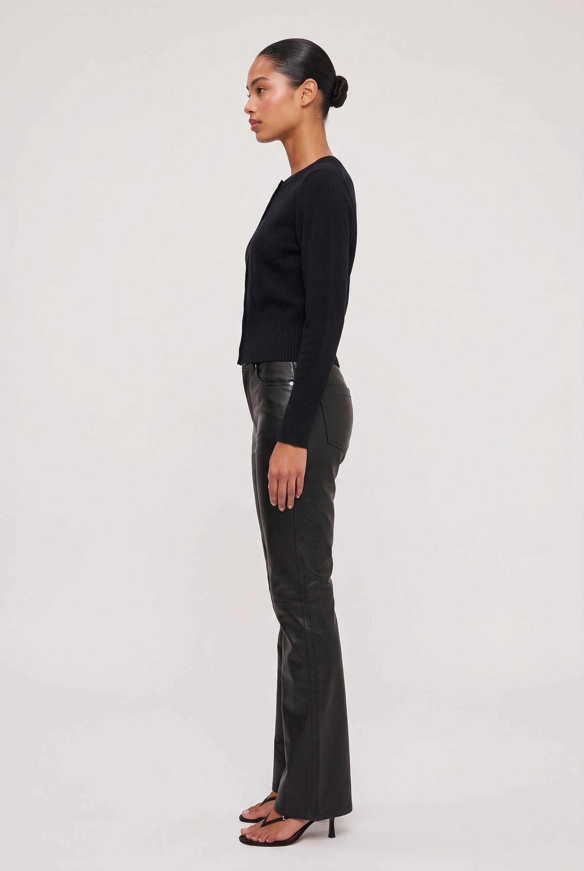 [Black] model wearing Vegan Leather Flare Pant posing Side View