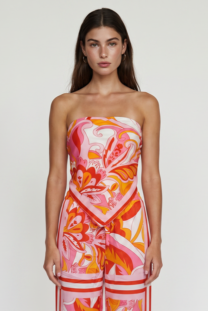 
Image shoes a girl thigh up standing straight looking at the camera wearing a printed strapless top and matching pants.